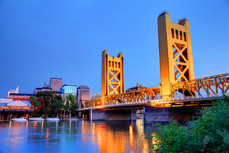 A bridge over a river with buildings in the background.