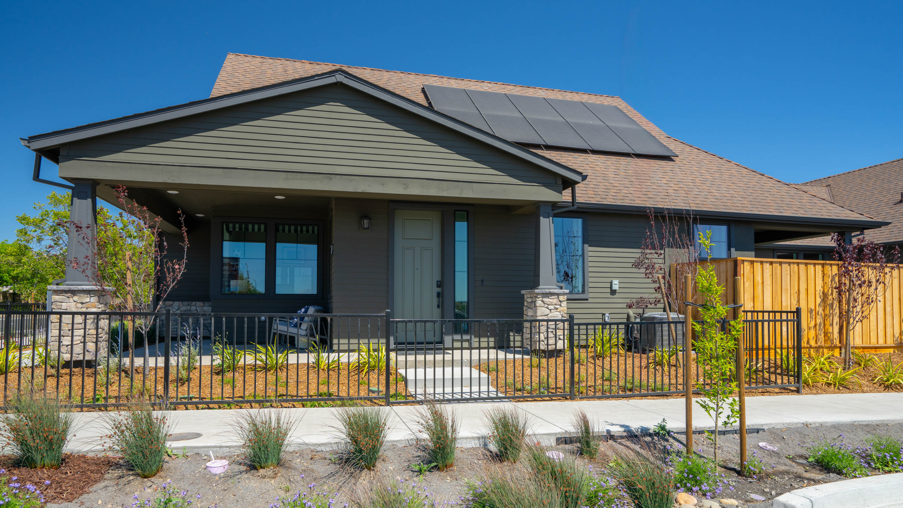 A house with a fence and bushes in front of it.