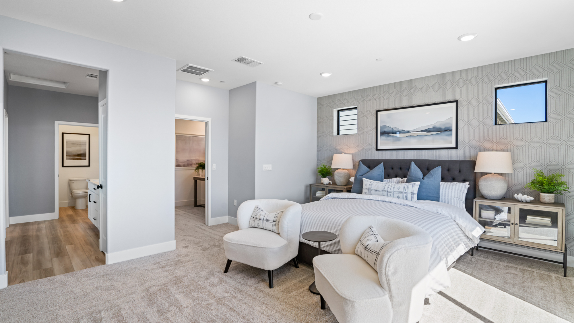 A bedroom with a bed and chairs.