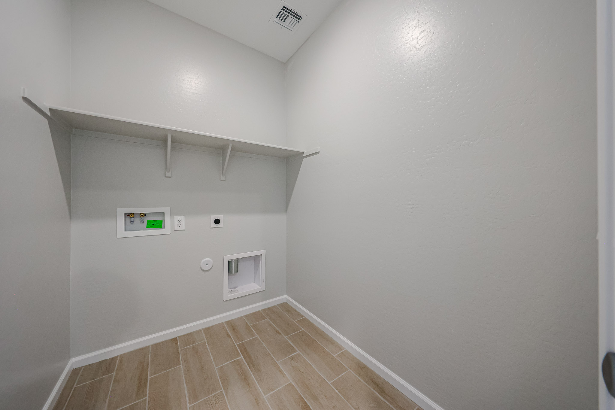 A room with a tile floor and a white wall with a light on it.