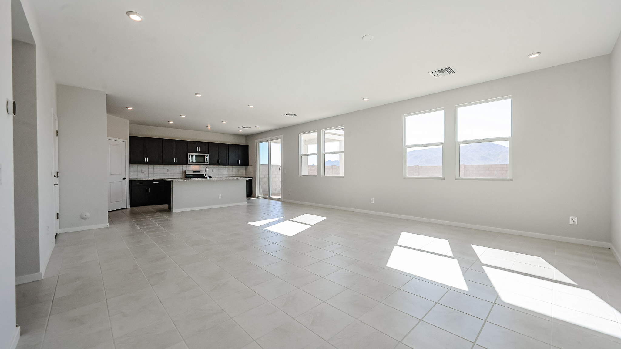 A large empty room with white tile floor and windows.