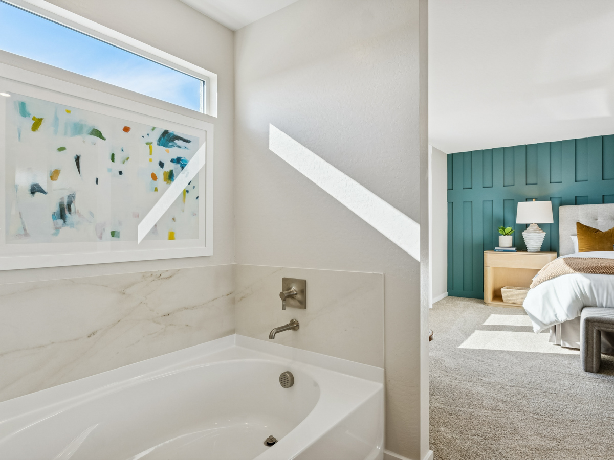 A bathroom with a tub and a bed.