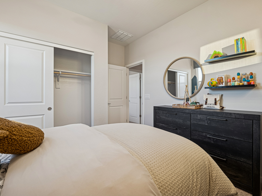 A bedroom with a bed and a mirror.