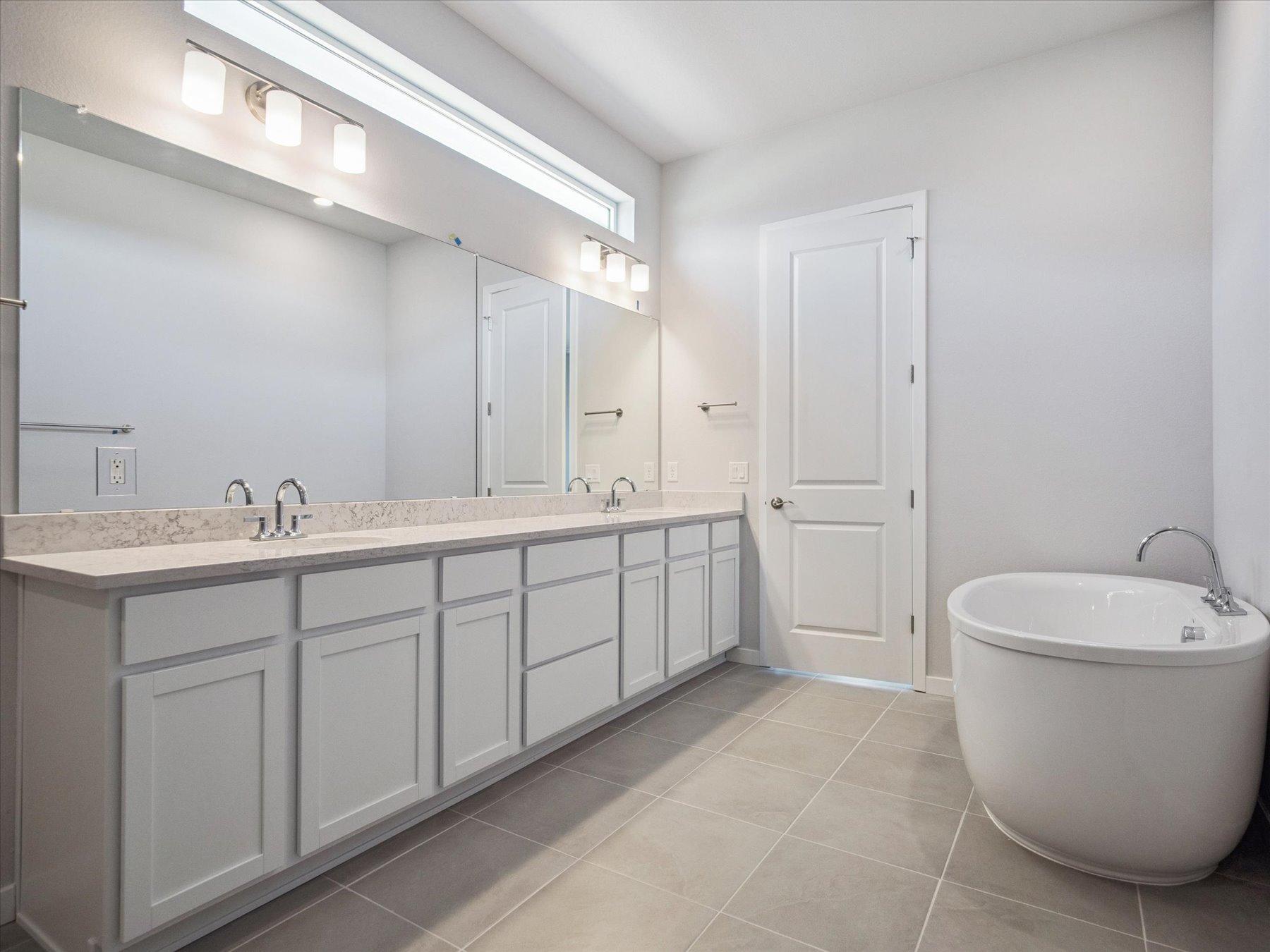 A bathroom with a tub sink and cabinets.