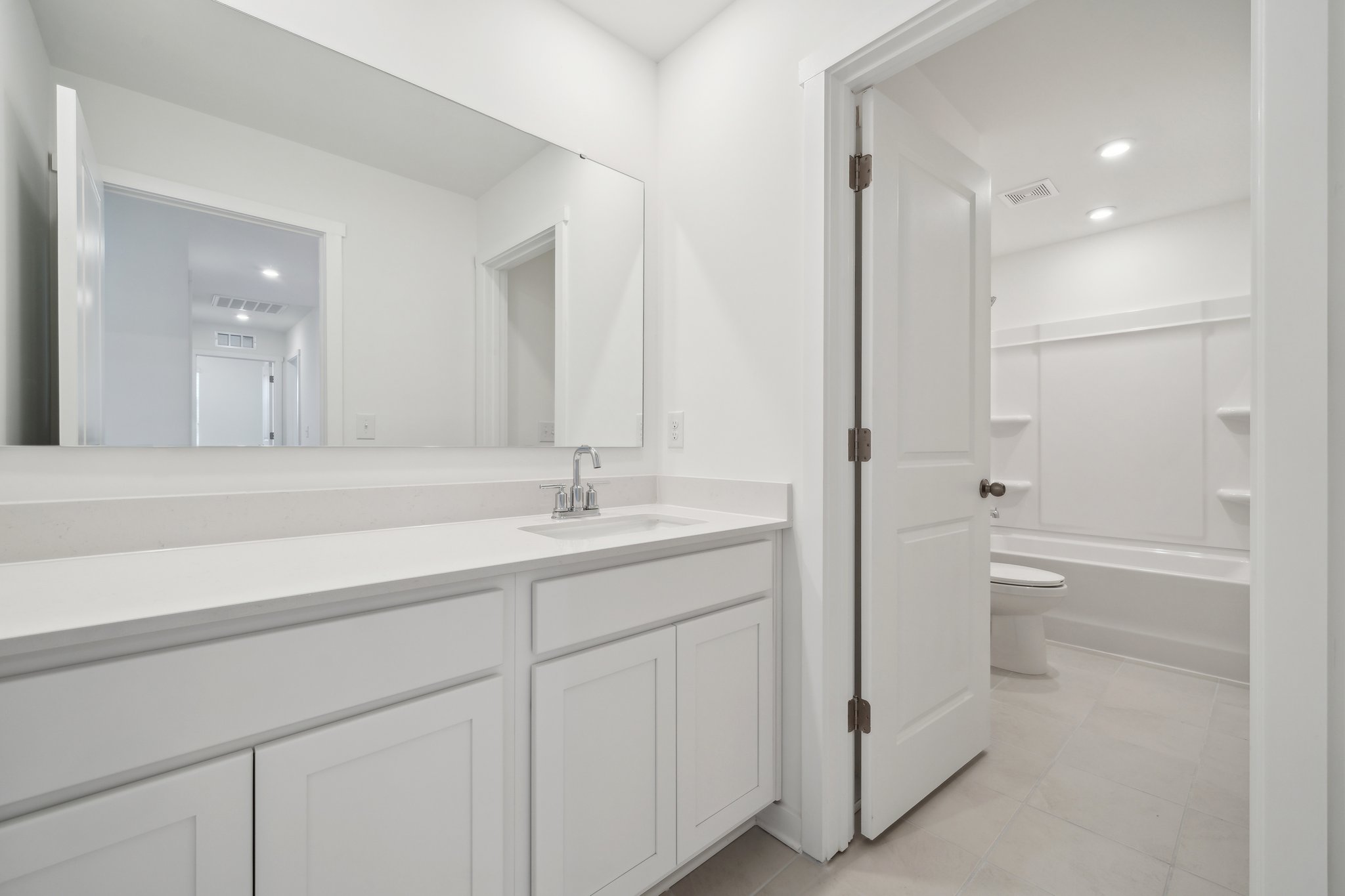 A bathroom with white cabinets.