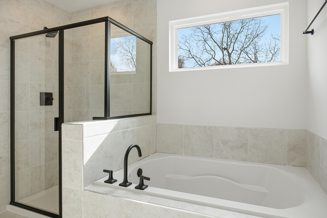 A bathtub and a window in a bathroom.
