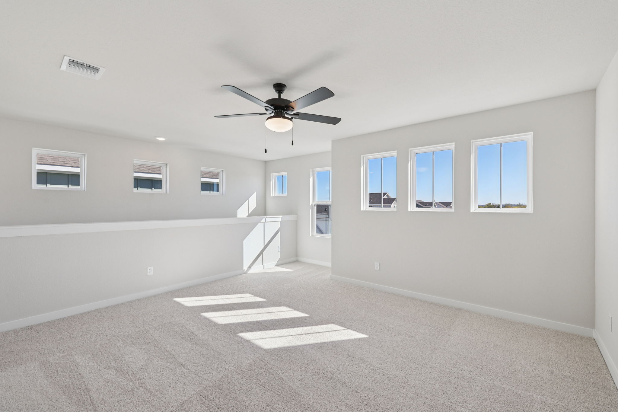 A room with a ceiling fan and a white wall with a white floor.