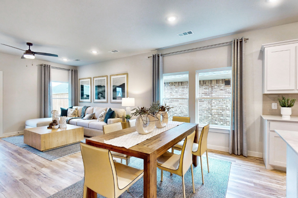 A large living room with a large dining table and a large window.