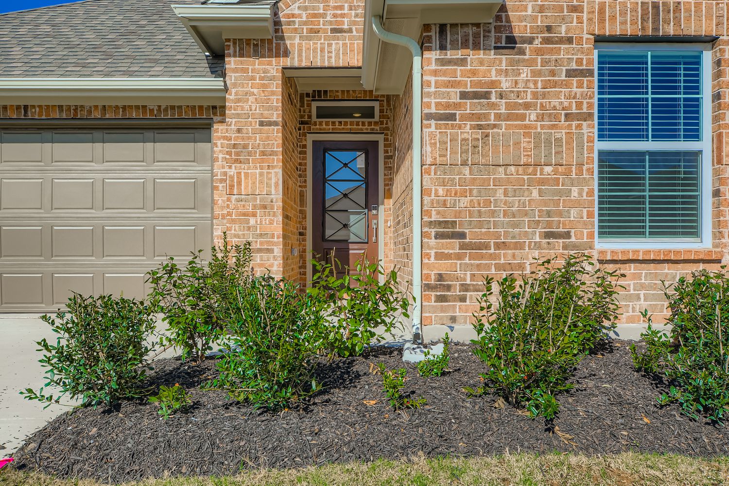 A brick building with a door and bushes in front of it.