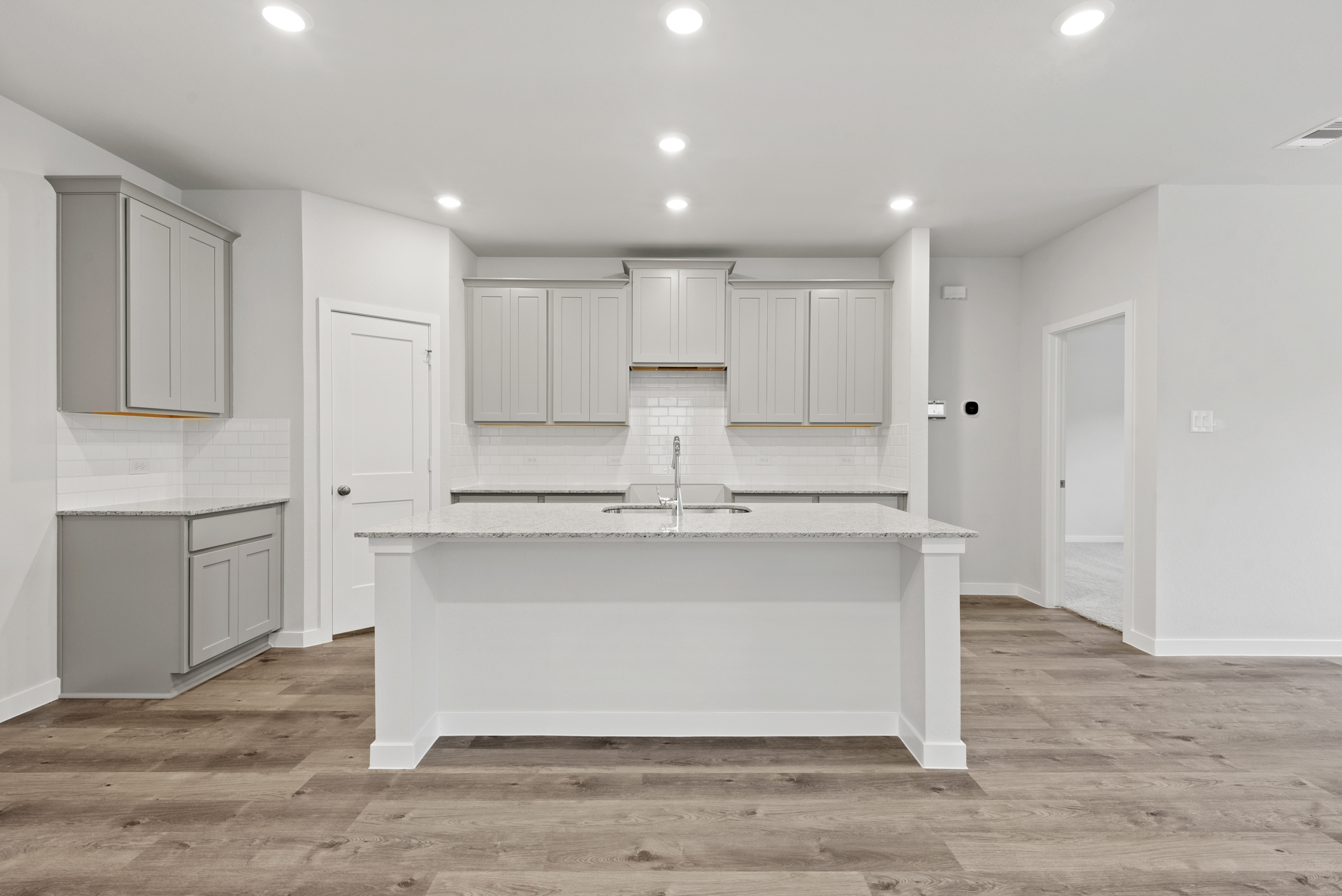 A white room with a bathtub and cabinets.