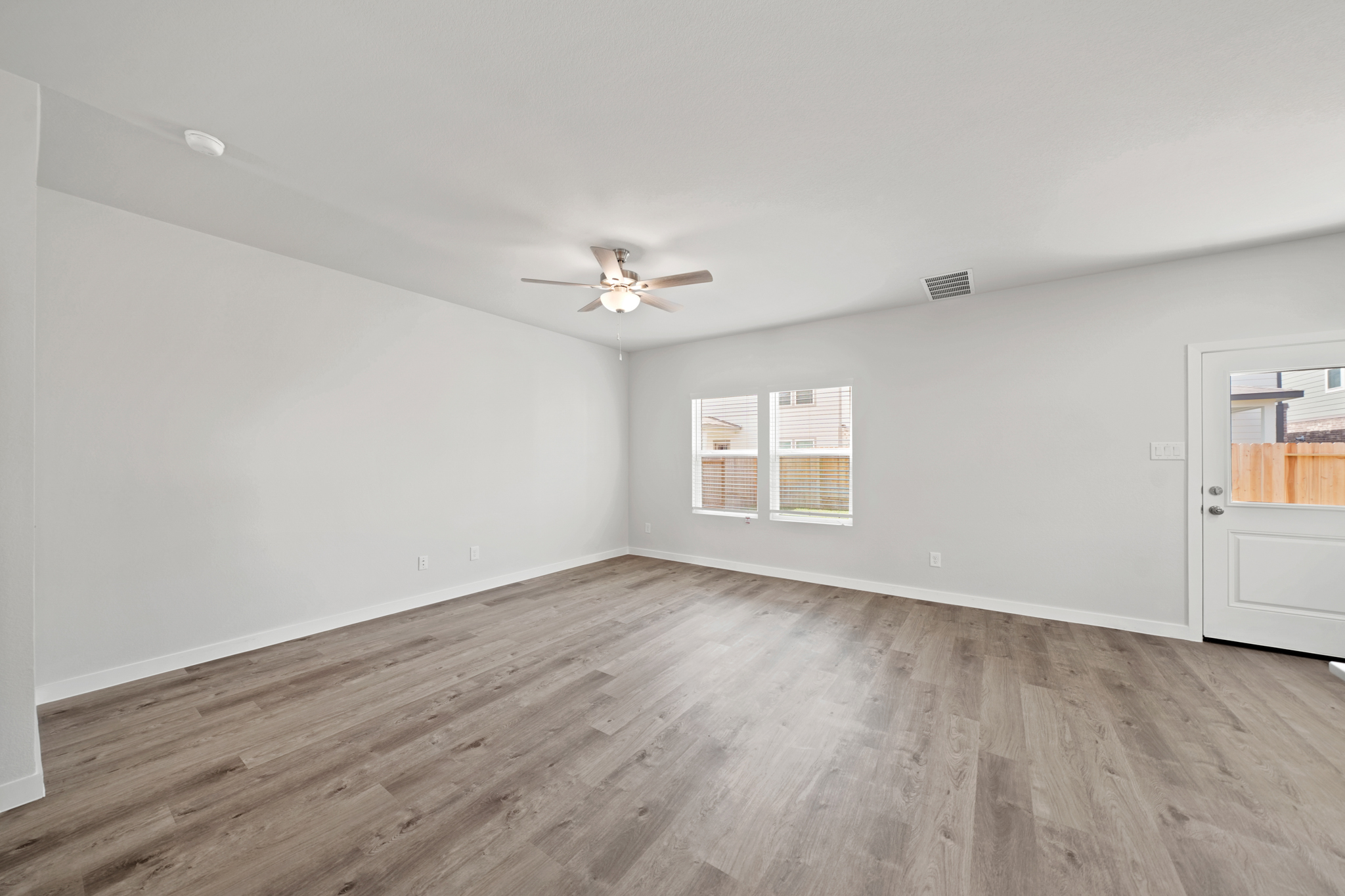 A room with a wood floor and a ceiling fan.