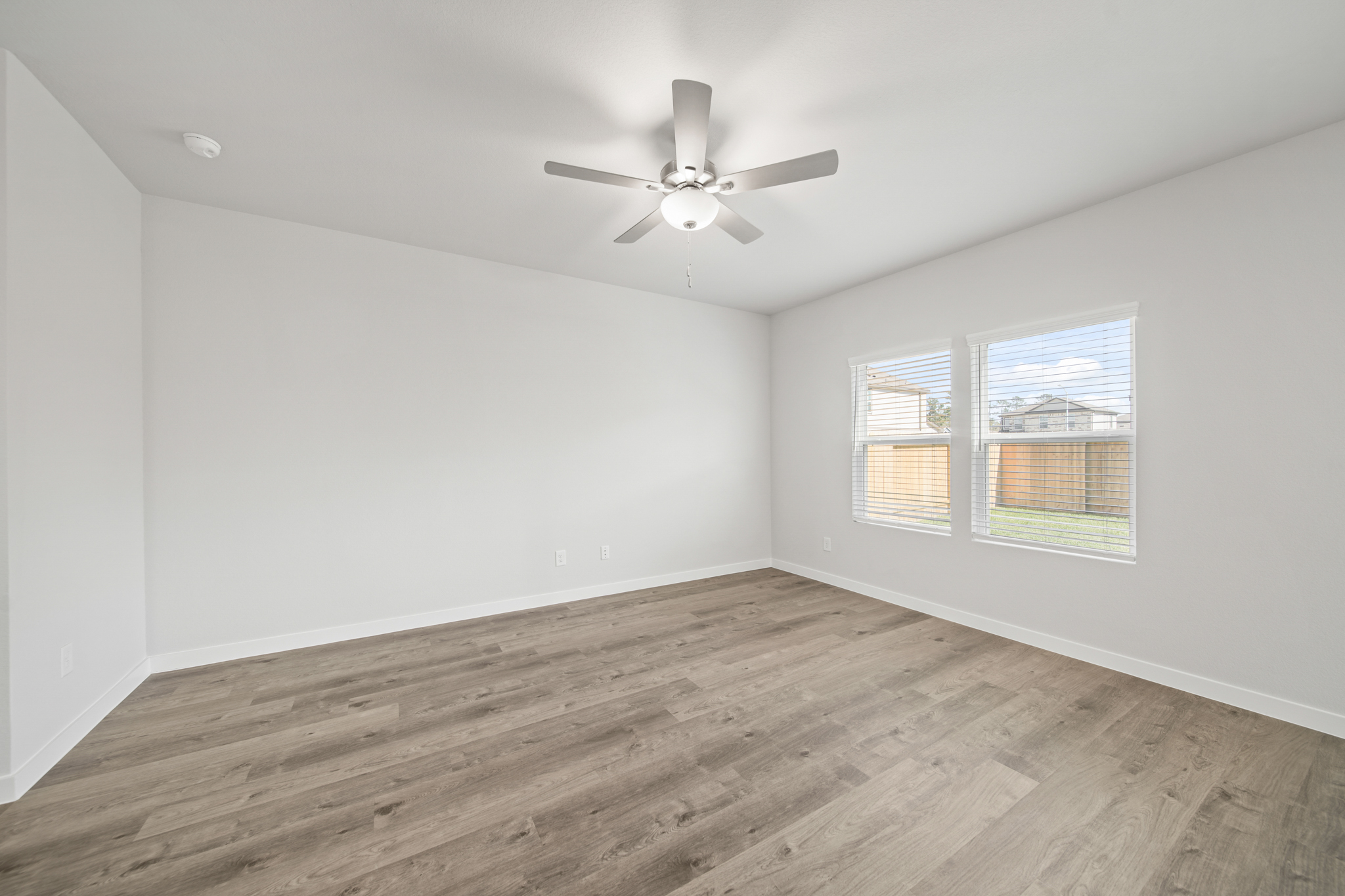 A room with a ceiling fan and a wood floor.
