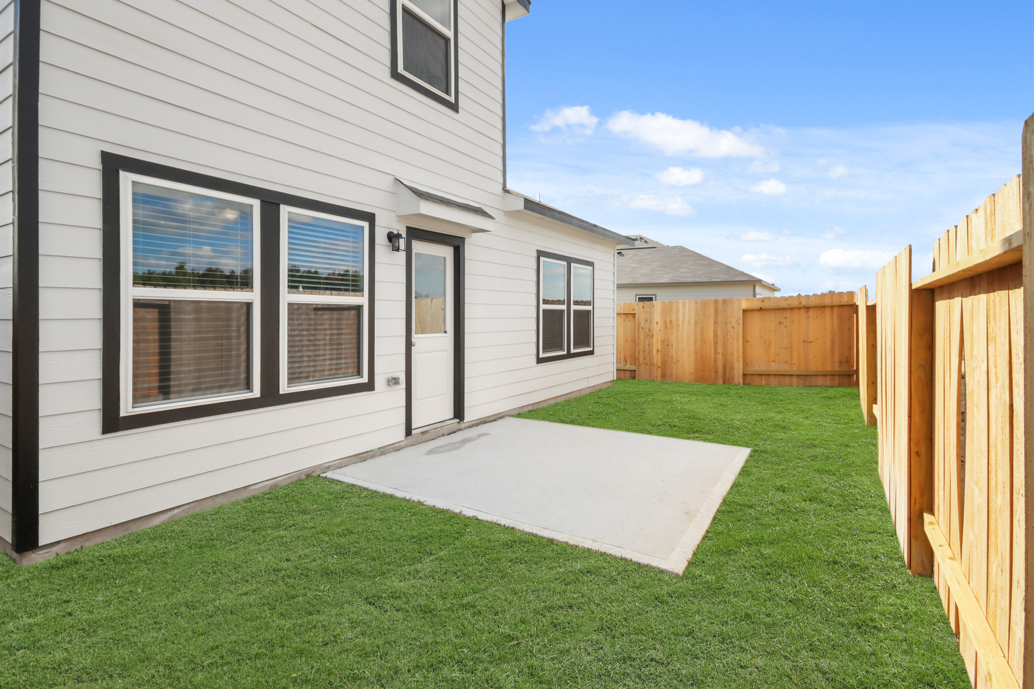 A backyard with a fence and a house.