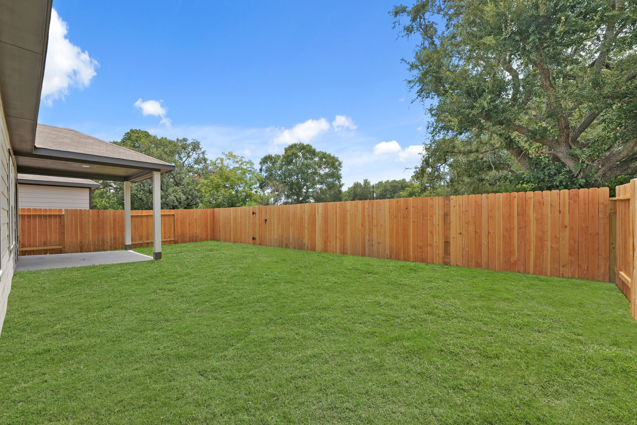 A fenced in yard with a wood fence and trees in the background.