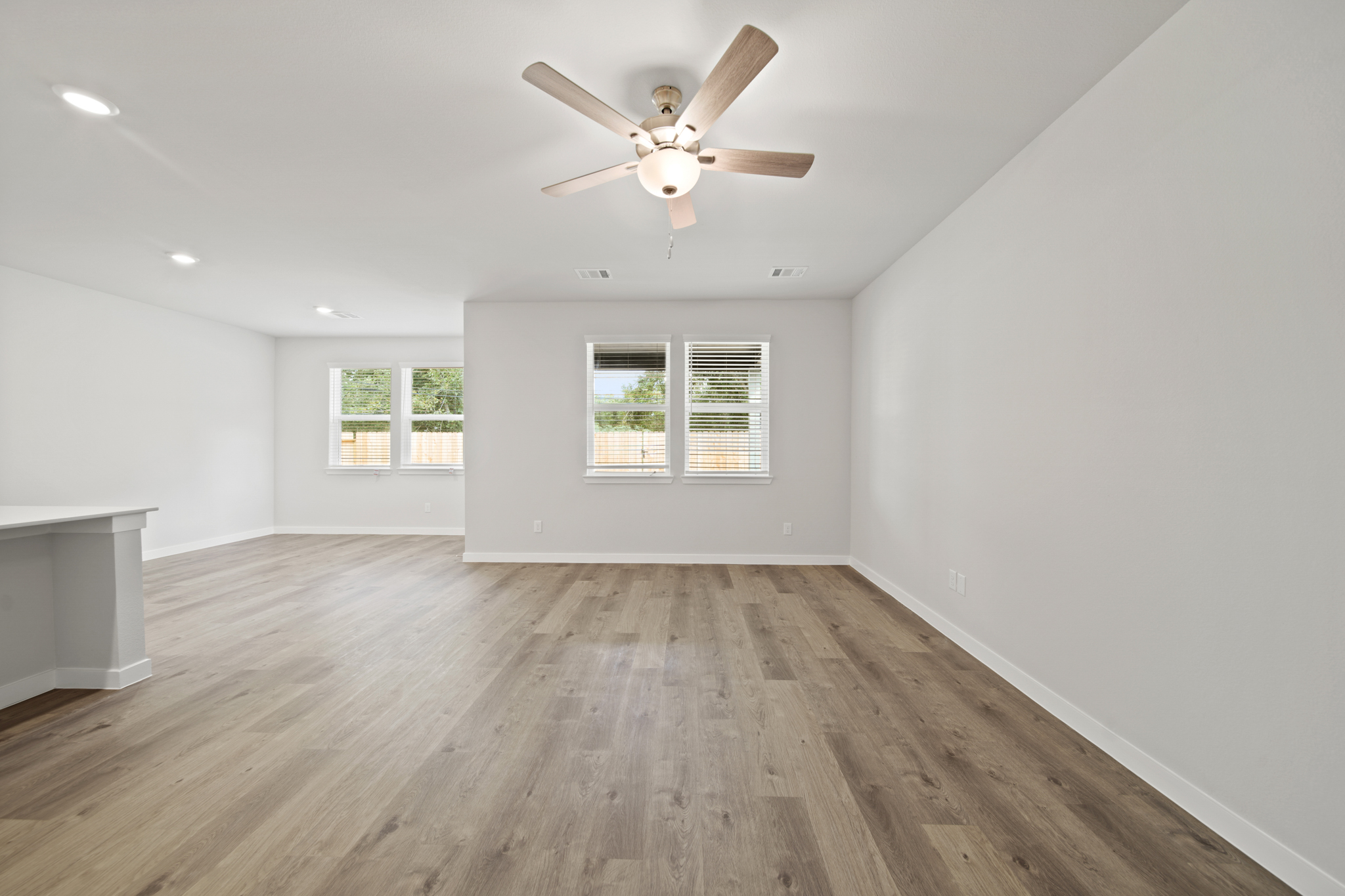 A room with a ceiling fan and a wood floor.