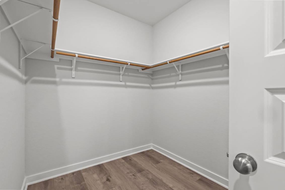 A white room with a wood floor and a metal bar.