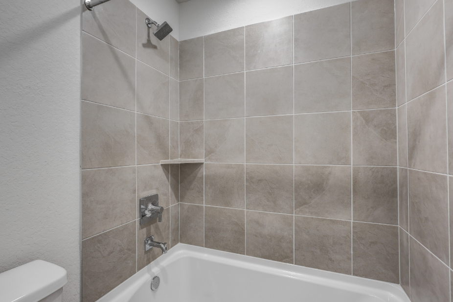 A bathtub with a tile wall.