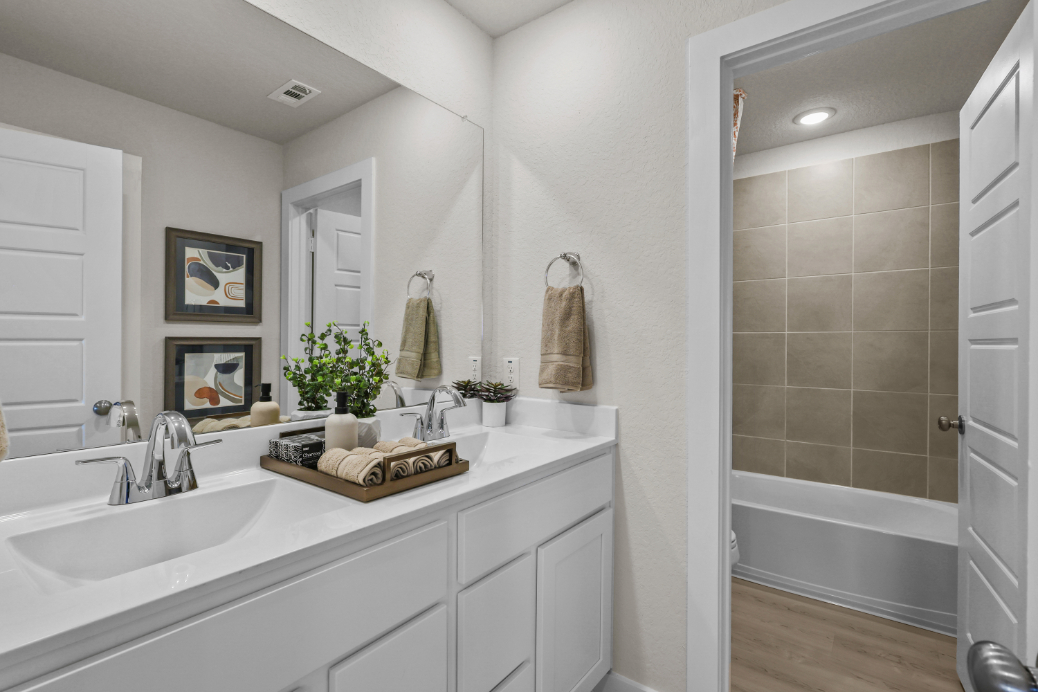A bathroom with a tub sink and a mirror.