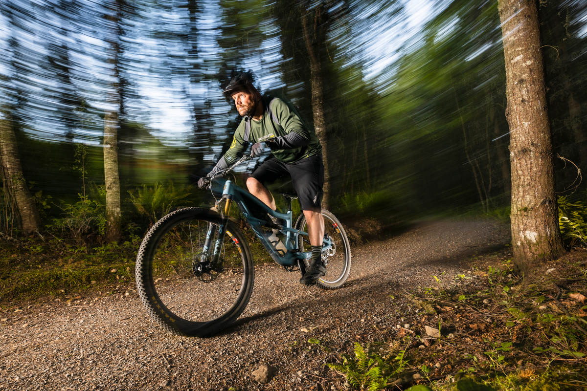A man riding a bike on a trail in the woods.