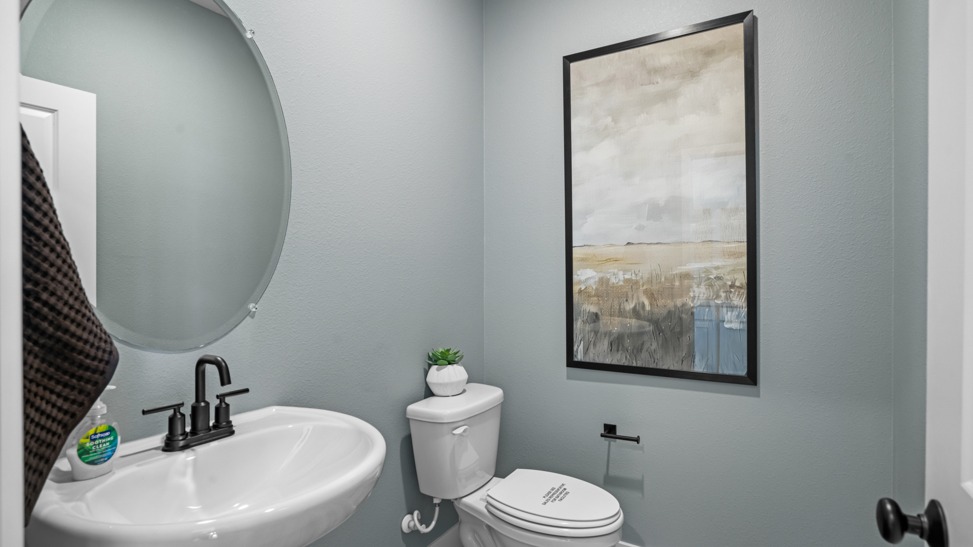 A bathroom with a large picture on the wall.